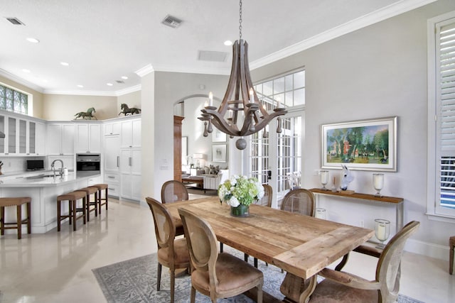 dining space with ornamental molding, sink, and a notable chandelier