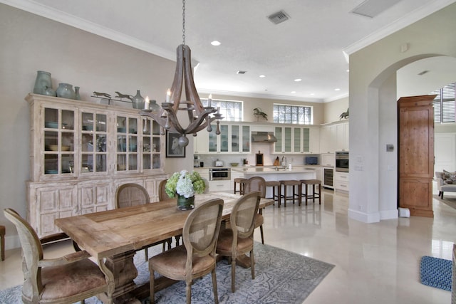 dining area featuring sink, crown molding, and a chandelier