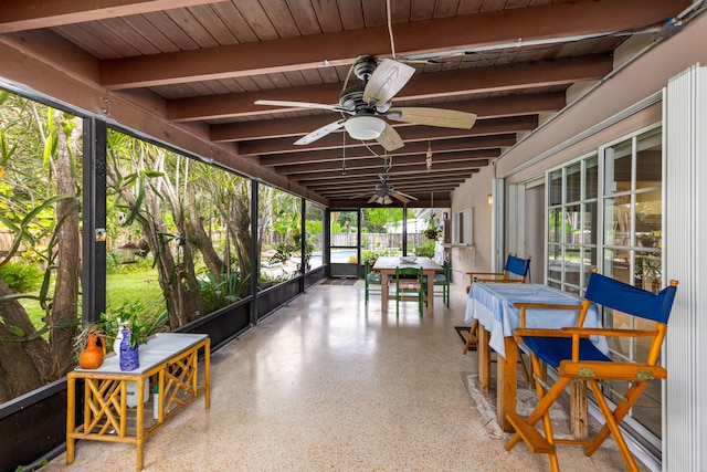 sunroom / solarium featuring beamed ceiling, wooden ceiling, ceiling fan, and a healthy amount of sunlight