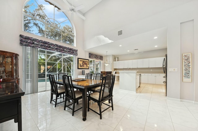 tiled dining area with a towering ceiling and ceiling fan