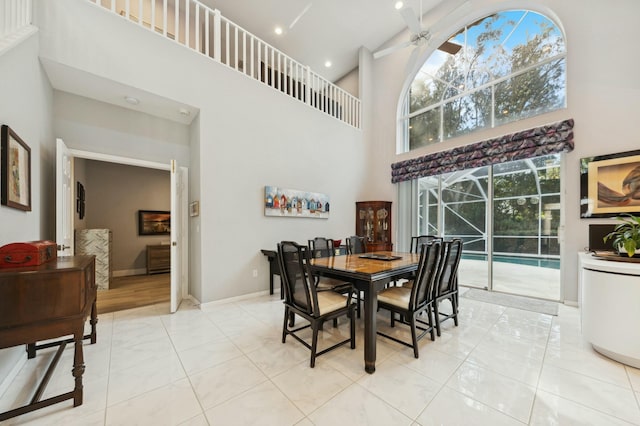 dining area featuring ceiling fan, a towering ceiling, and light tile patterned floors