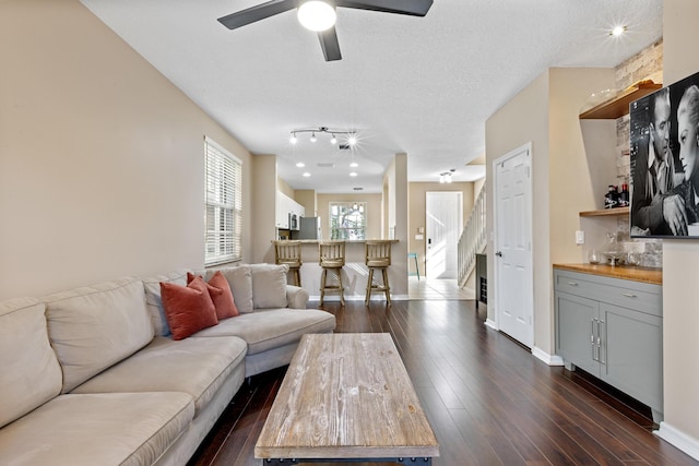 living room featuring dark hardwood / wood-style floors, ceiling fan, and a textured ceiling