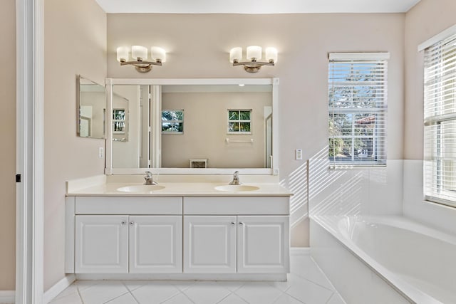 bathroom featuring a washtub, vanity, a healthy amount of sunlight, and tile patterned flooring