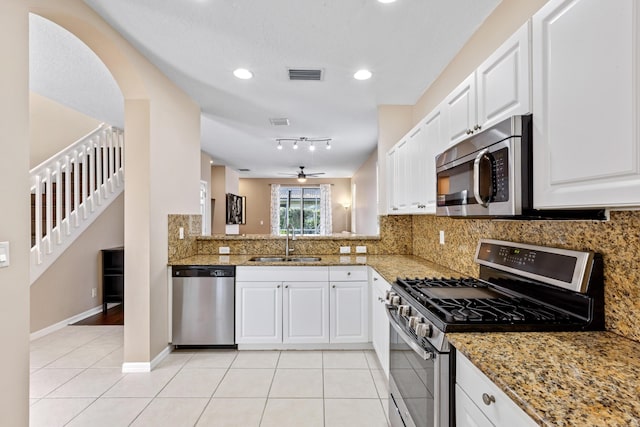 kitchen with white cabinets, sink, light tile patterned floors, appliances with stainless steel finishes, and stone countertops