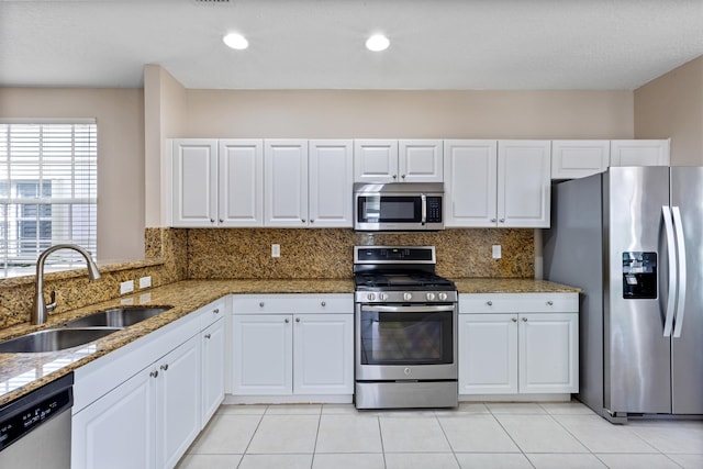 kitchen with decorative backsplash, stainless steel appliances, white cabinetry, and sink