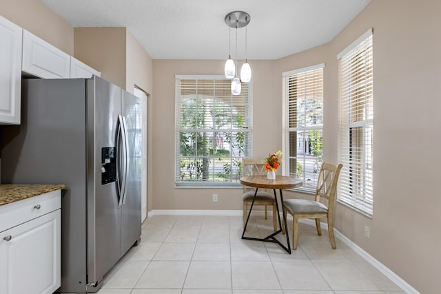 kitchen with decorative light fixtures, white cabinetry, stainless steel fridge with ice dispenser, and dark stone counters