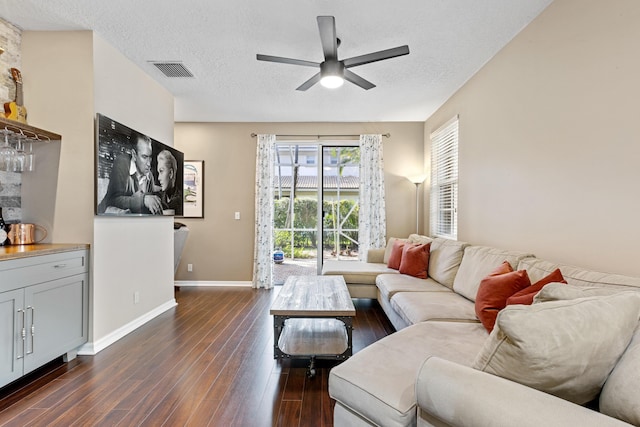 living room with dark hardwood / wood-style floors, ceiling fan, and a textured ceiling