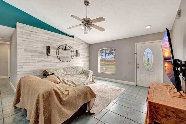 living room with ceiling fan, light tile patterned flooring, a textured ceiling, and vaulted ceiling