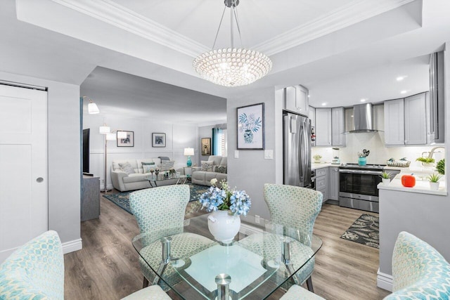 dining area featuring baseboards, a tray ceiling, light wood-type flooring, and crown molding