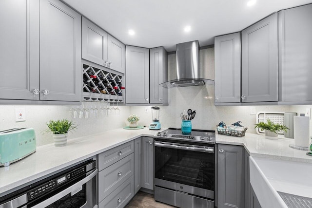 kitchen with gray cabinetry, light countertops, wall chimney range hood, and stainless steel electric stove