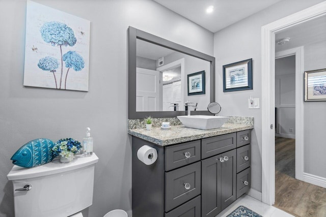 full bath featuring toilet, baseboards, wood finished floors, and vanity