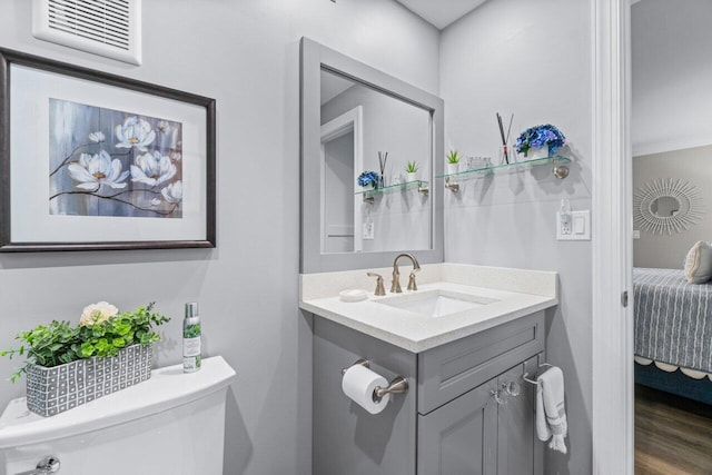 ensuite bathroom with visible vents, toilet, ensuite bathroom, vanity, and wood finished floors