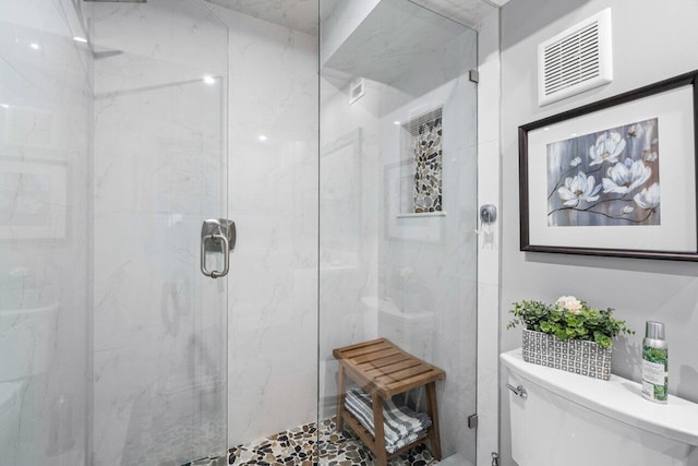 bathroom featuring toilet, a stall shower, and visible vents