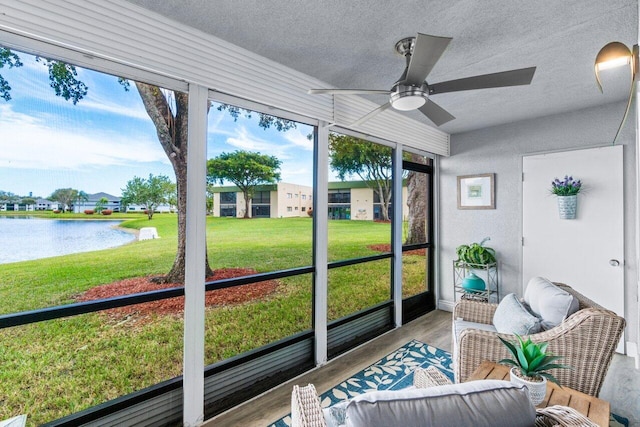 sunroom / solarium with ceiling fan and a water view