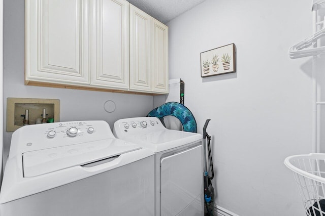 laundry area with cabinet space, independent washer and dryer, and a textured ceiling