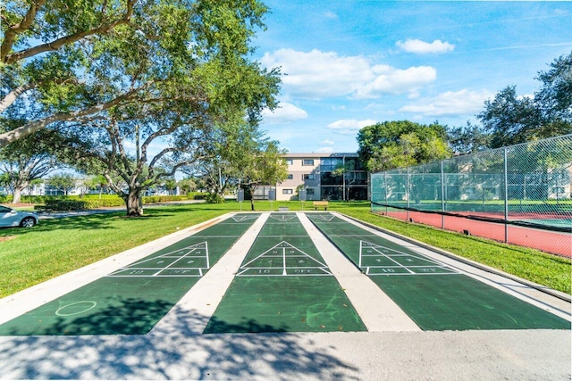 view of property's community featuring a yard, fence, and shuffleboard