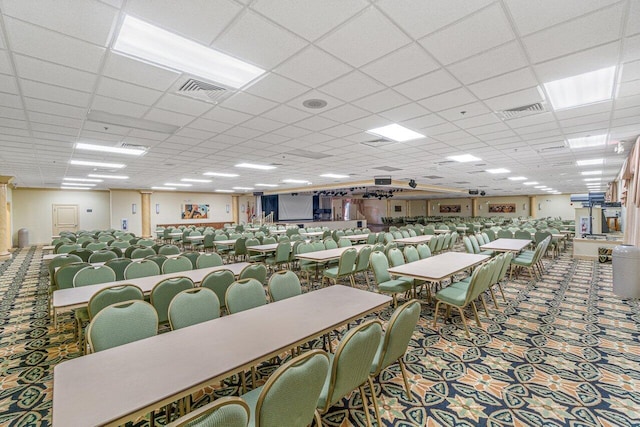 carpeted dining space with a paneled ceiling and visible vents