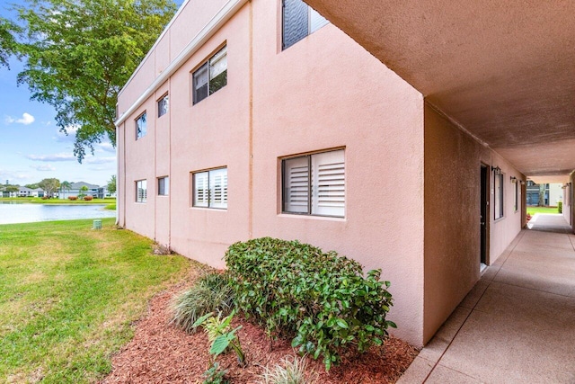 view of side of home with a lawn, a water view, and stucco siding