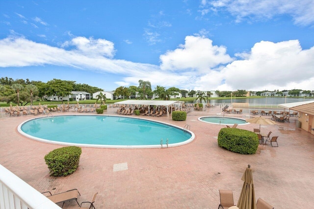 community pool featuring a community hot tub, a water view, and a patio