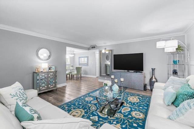 living room featuring baseboards, visible vents, wood finished floors, and ornamental molding