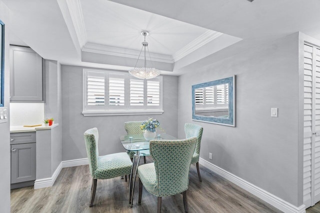 dining area featuring a tray ceiling, crown molding, and wood finished floors