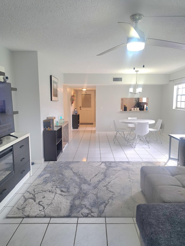 living room featuring ceiling fan, a textured ceiling, and light tile patterned flooring