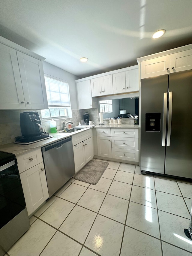 kitchen featuring stainless steel appliances, decorative backsplash, white cabinets, and sink