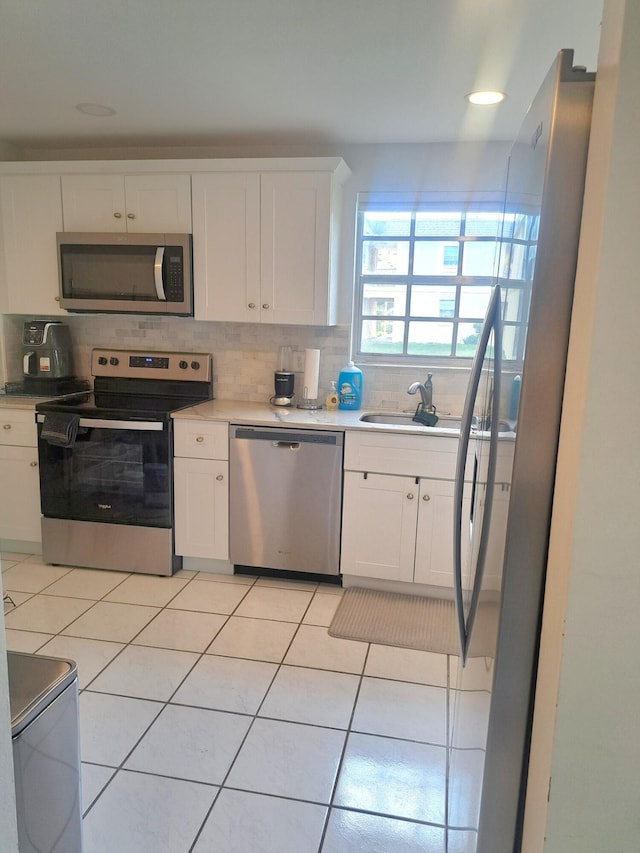 kitchen featuring white cabinets, sink, light tile patterned floors, and stainless steel appliances