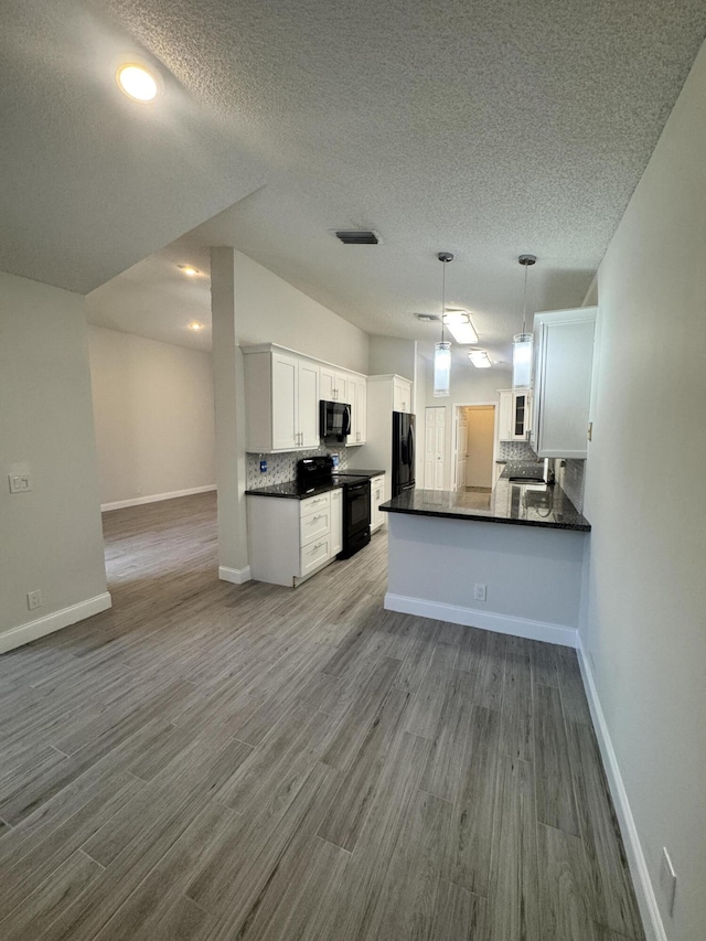 kitchen with black appliances, kitchen peninsula, white cabinetry, and backsplash