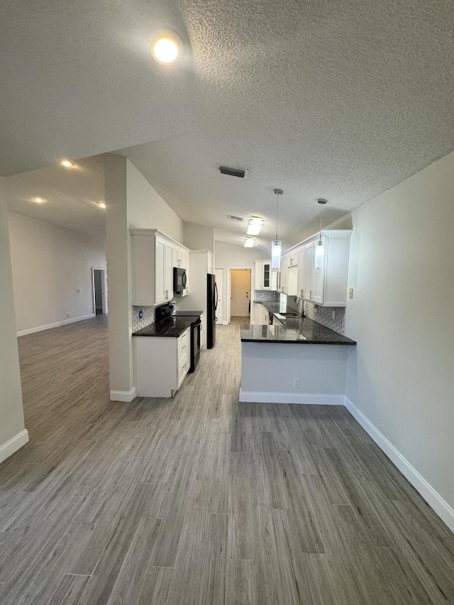 kitchen with kitchen peninsula, decorative backsplash, white cabinetry, and lofted ceiling