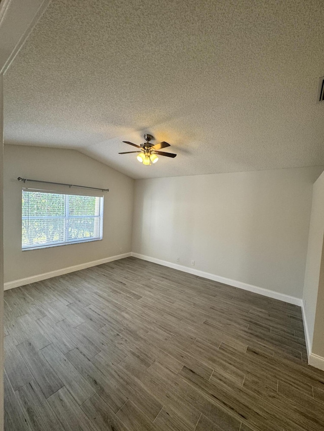 unfurnished room with a textured ceiling, ceiling fan, dark wood-type flooring, and vaulted ceiling