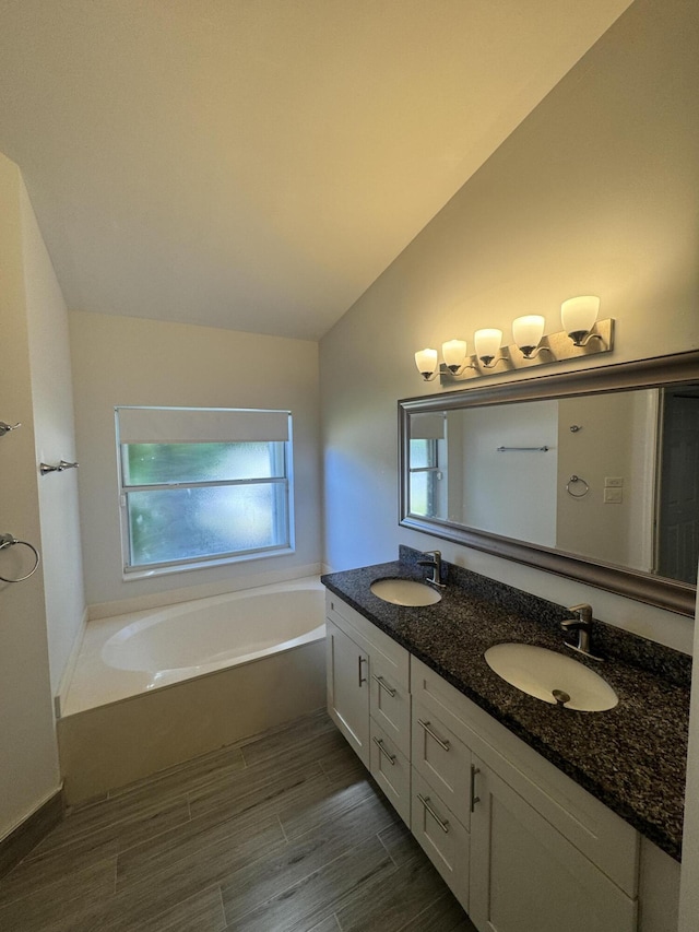 bathroom featuring vanity, vaulted ceiling, and a bathtub