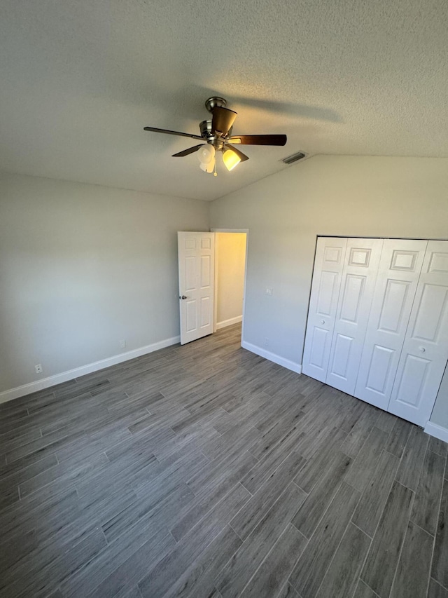 unfurnished bedroom with a textured ceiling, ceiling fan, a closet, and lofted ceiling