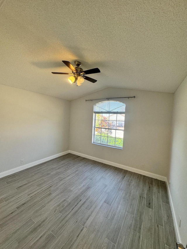 spare room featuring hardwood / wood-style floors, a textured ceiling, vaulted ceiling, and ceiling fan