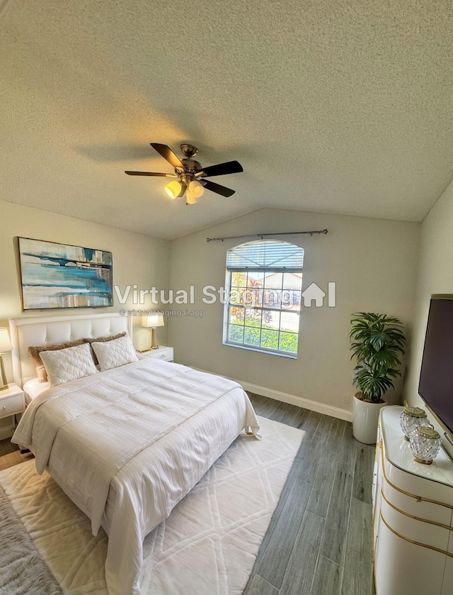 bedroom with a textured ceiling, ceiling fan, lofted ceiling, and hardwood / wood-style flooring