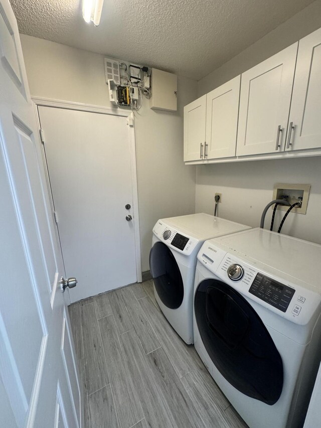 laundry room featuring cabinets, a textured ceiling, and washing machine and clothes dryer