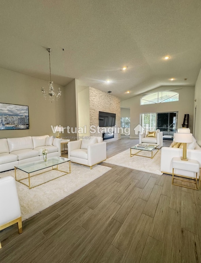 living room with a textured ceiling, vaulted ceiling, and a notable chandelier