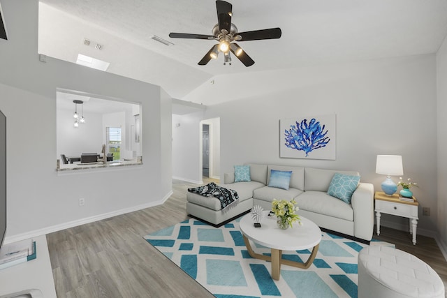 living room with vaulted ceiling, wood finished floors, visible vents, and baseboards