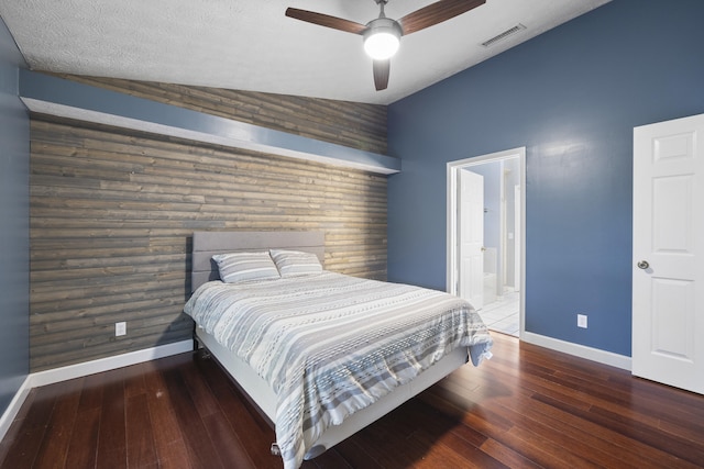 bedroom with baseboards, visible vents, lofted ceiling, an accent wall, and hardwood / wood-style floors