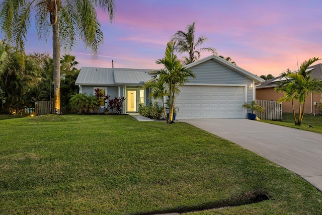 ranch-style house featuring a garage, concrete driveway, fence, and a lawn