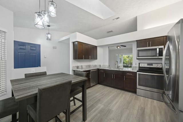 kitchen featuring visible vents, stainless steel appliances, dark brown cabinets, light countertops, and a sink