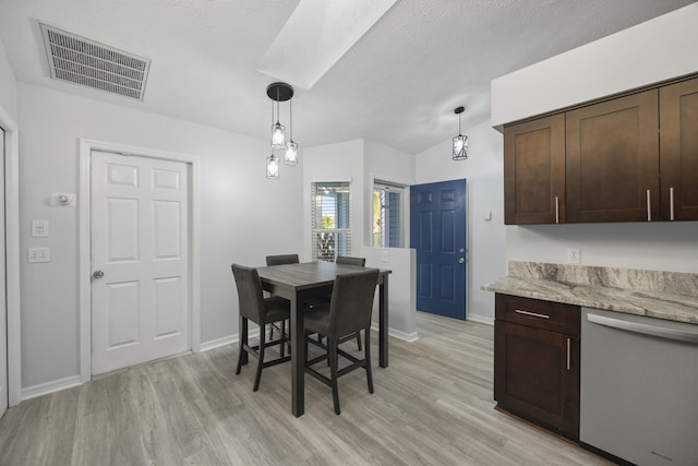 dining room featuring light wood-type flooring, lofted ceiling, and a textured ceiling