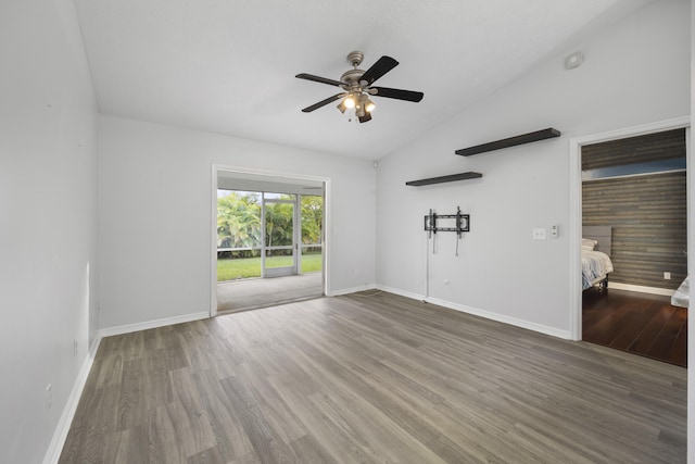 empty room with ceiling fan, dark hardwood / wood-style floors, and vaulted ceiling