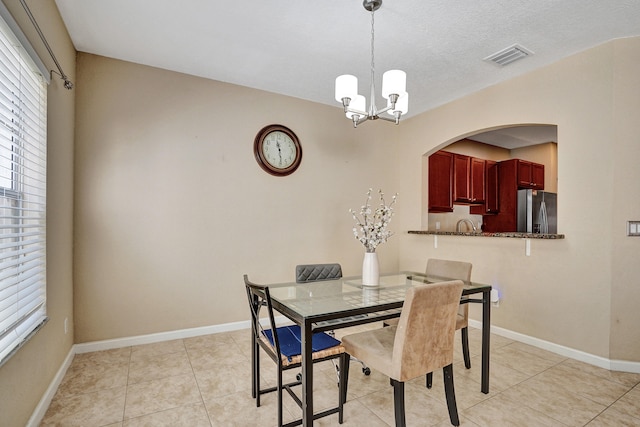 dining room with light tile patterned flooring, a textured ceiling, and an inviting chandelier