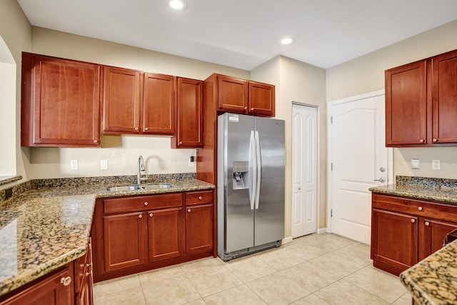 kitchen featuring stone counters, stainless steel refrigerator with ice dispenser, light tile patterned flooring, and sink