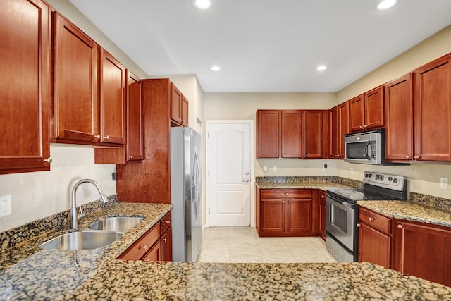 kitchen featuring stone counters, sink, light tile patterned flooring, and appliances with stainless steel finishes