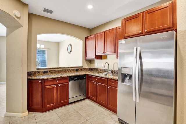 kitchen featuring dark stone counters, sink, light tile patterned floors, and stainless steel appliances