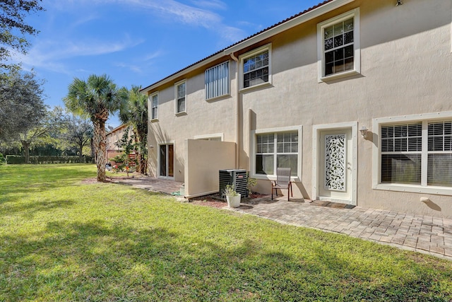 rear view of property with a yard, central AC unit, and a patio area