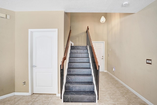 staircase with tile patterned floors and a textured ceiling