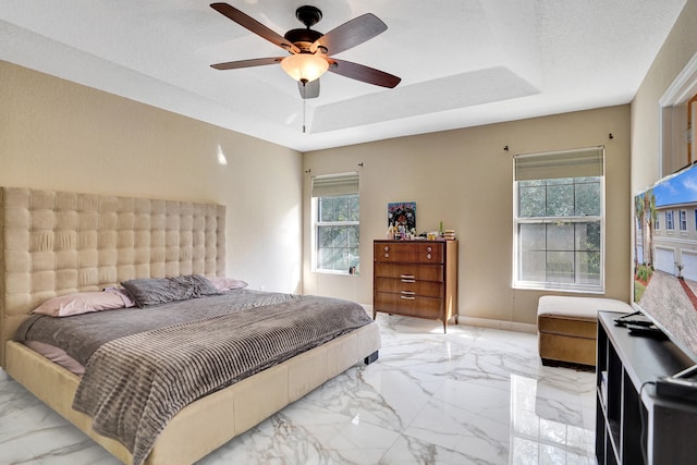 bedroom featuring multiple windows, a textured ceiling, a raised ceiling, and ceiling fan